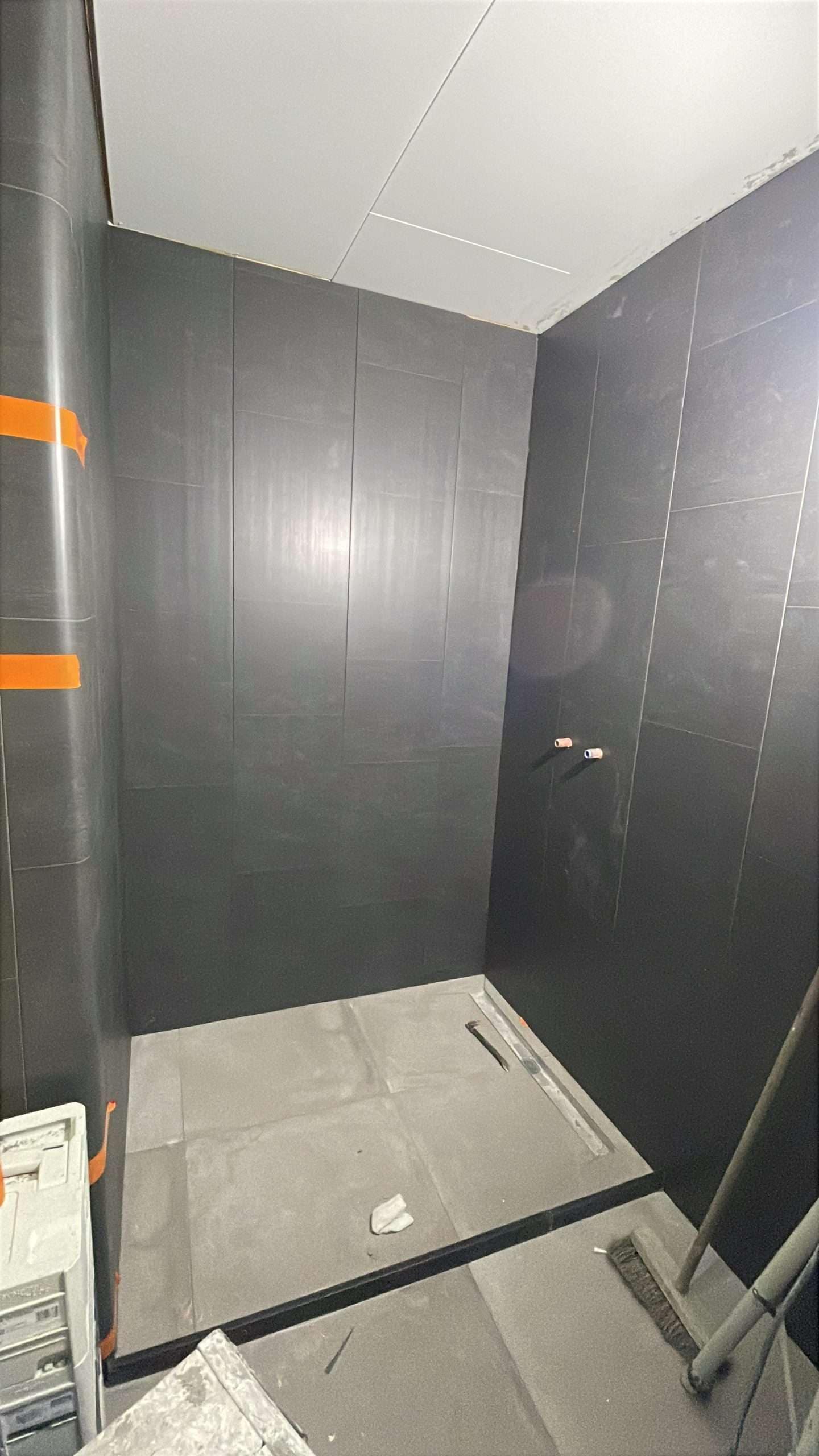 Portfolio Badkamer in aanbouw met betegelde vloer, PVC wandpanelen en Agnes plafondplaten door NJB Klussen in Hoogezand